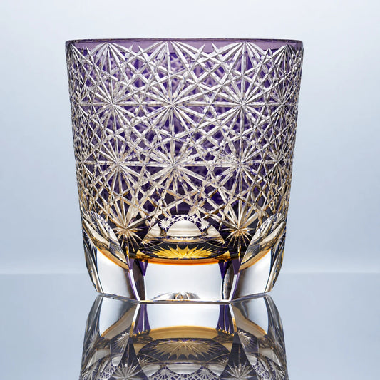 A large purple hand-cut Edo Kiriko crystal whiskey glass featuring dense daisy-inspired starburst cut patterns, a rich violet tone, and a polished clear base in a reflective studio setting.