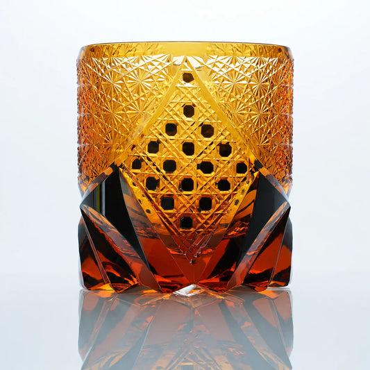 A front view of the Black Warrior hand-cut Edo Kiriko whiskey glass featuring amber crystal tones, a geometric hexagonal center panel, and bold dark faceted details.