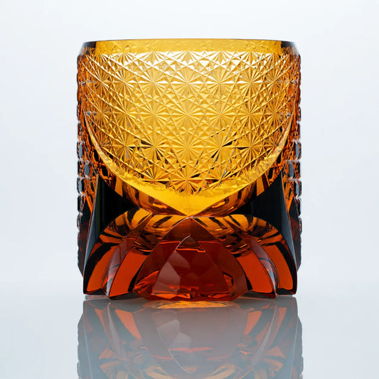 A back view of the Black Warrior hand-cut Edo Kiriko whiskey glass featuring dense starburst cut patterns, warm amber crystal tones, and a sculpted faceted base.