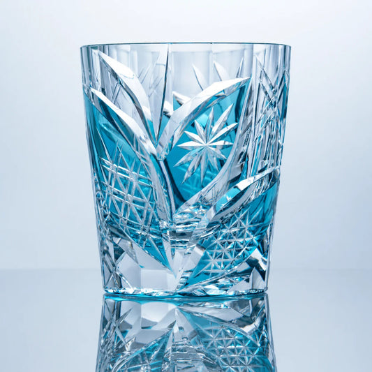 An aqua hand-cut Edo Kiriko whiskey glass featuring bright teal-blue crystal tones, leaf-like faceted cuts, starburst detailing, and a polished reflective studio presentation.