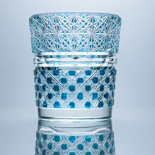 A hand-cut aqua Edo Kiriko whiskey glass featuring jewel-like circular crystal cuts, intricate starburst patterns, clear polished bands, and a reflective studio presentation.