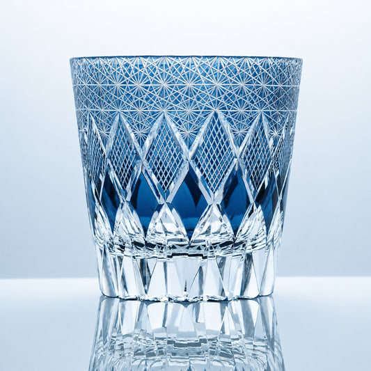 A hand-cut Edo Kiriko whiskey glass featuring sapphire-blue crystal, dense starburst engraving, and a distinctive diamond lattice middle band.