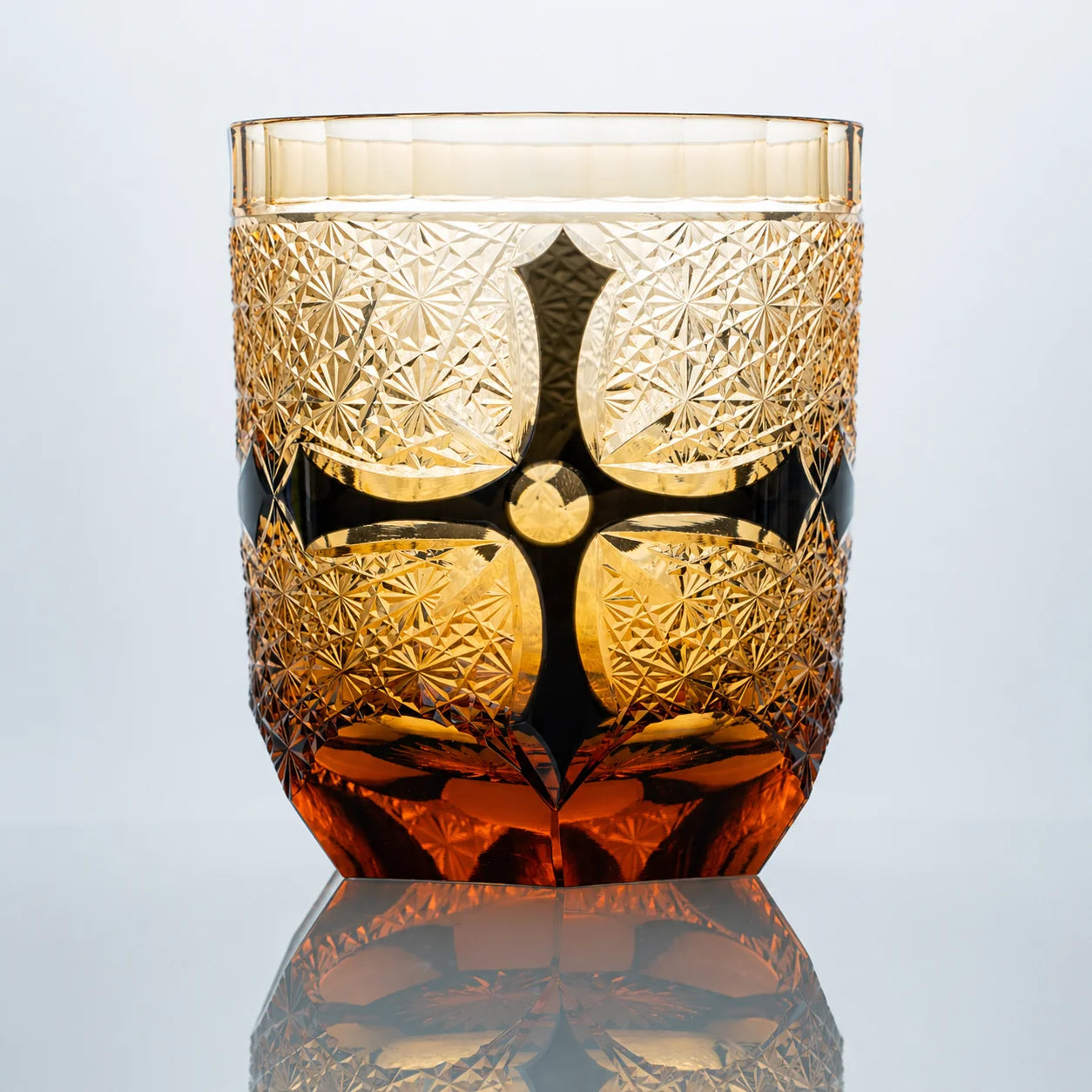 Amber black Edo Kiriko whiskey glass with hand-cut crystal starburst patterns and dark obsidian accents.