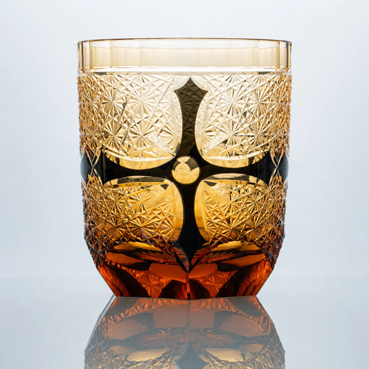 Amber black Edo Kiriko whiskey glass with hand-cut crystal starburst patterns and dark obsidian accents.