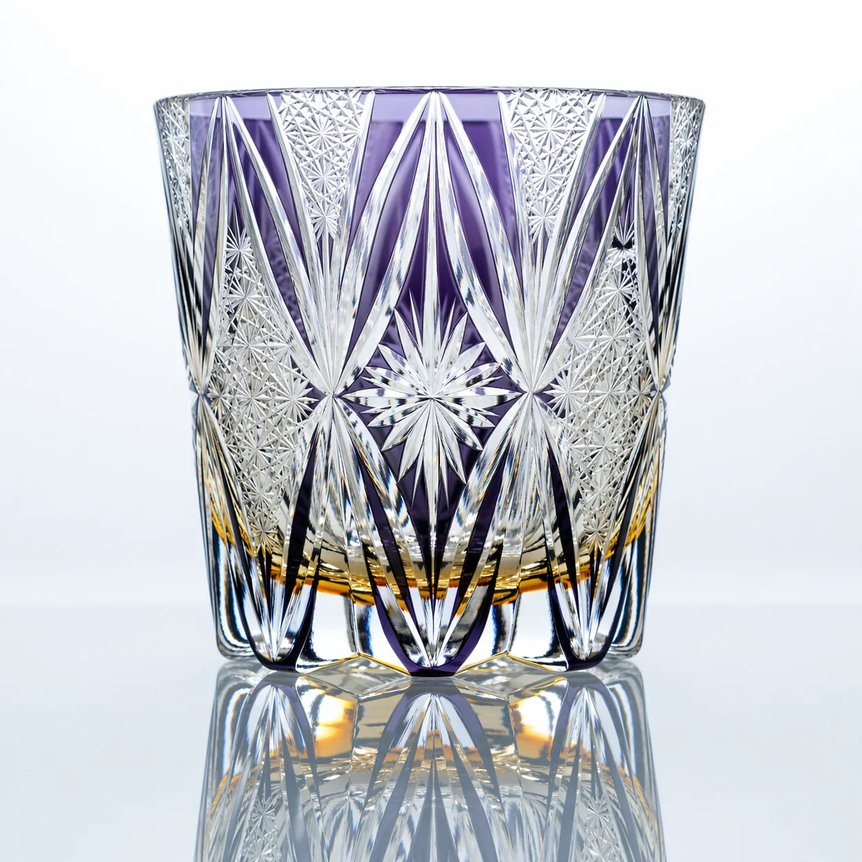 An amethyst hand-cut Edo Kiriko whiskey glass featuring elongated fan-cut crystal details, fine geometric textures, a central starburst motif, and a polished reflective studio presentation.