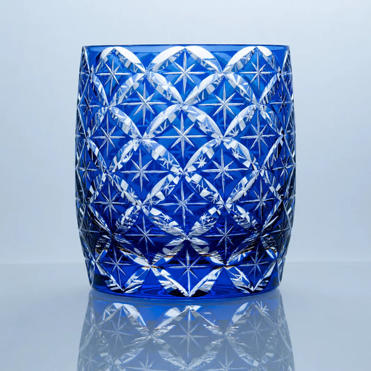 A blue hand-cut Edo Kiriko whiskey glass featuring repeating star motifs, an intricate geometric lattice pattern, and a polished reflective studio presentation.