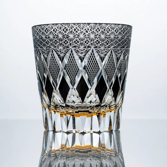 A smoke black hand-cut Edo Kiriko whiskey glass featuring sharp diamond lattice cuts, dense starburst crystal patterns, and a polished reflective studio presentation.