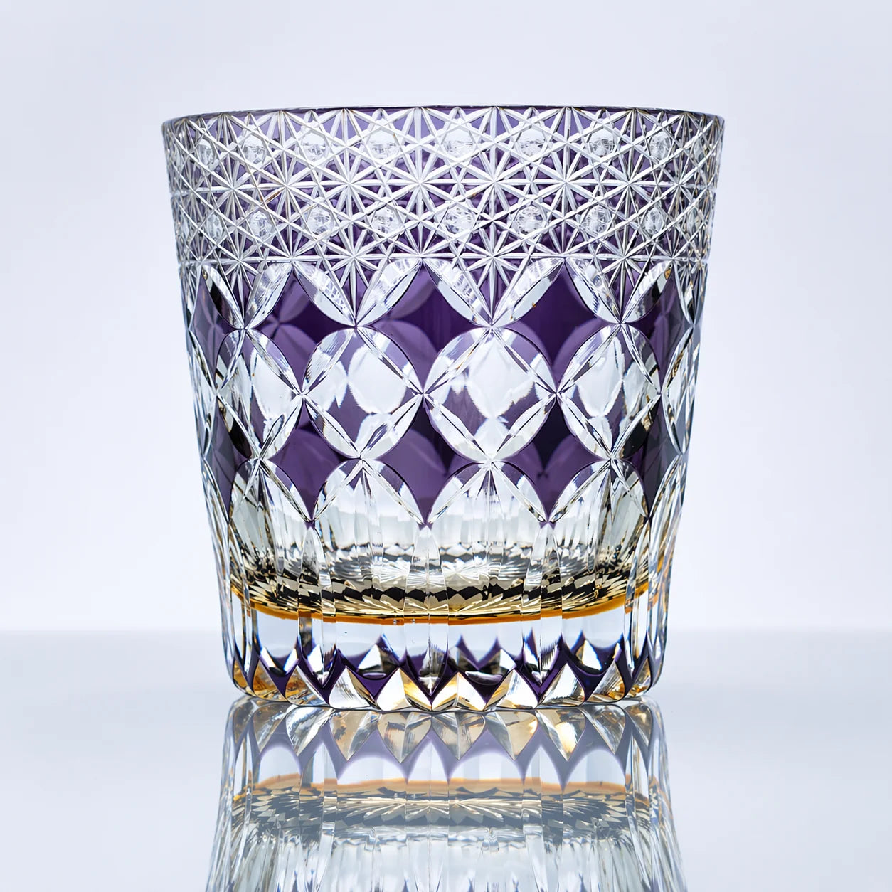 An amethyst hand-cut Edo Kiriko whiskey glass featuring fine lattice starburst cuts, a rich violet mosaic-style band, clear faceted crystal detailing, and a polished reflective studio presentation.