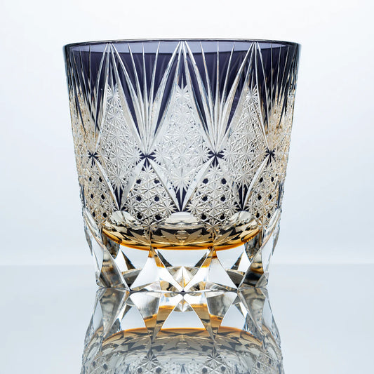 An indigo hand-cut Edo Kiriko whiskey glass featuring crown-like faceted cuts, intricate starburst engraving, clear crystal detailing, and a polished reflective studio presentation.