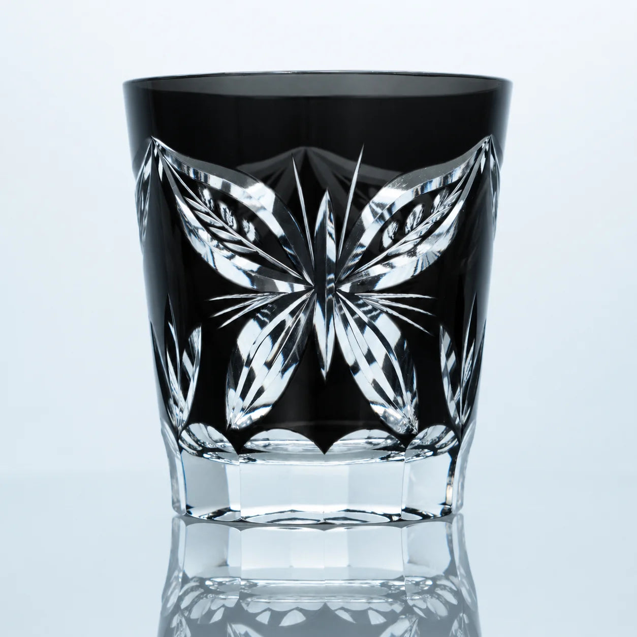 A handcrafted black crystal Edo Kiriko whiskey glass featuring a large butterfly-inspired cut pattern, clear faceted detailing, and a polished studio presentation.