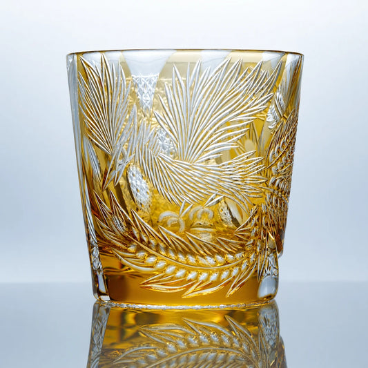 A hand-cut amber Edo Kiriko whiskey glass featuring phoenix-inspired feather motifs, intricate geometric patterns, polished crystal surfaces, and a reflective studio presentation.