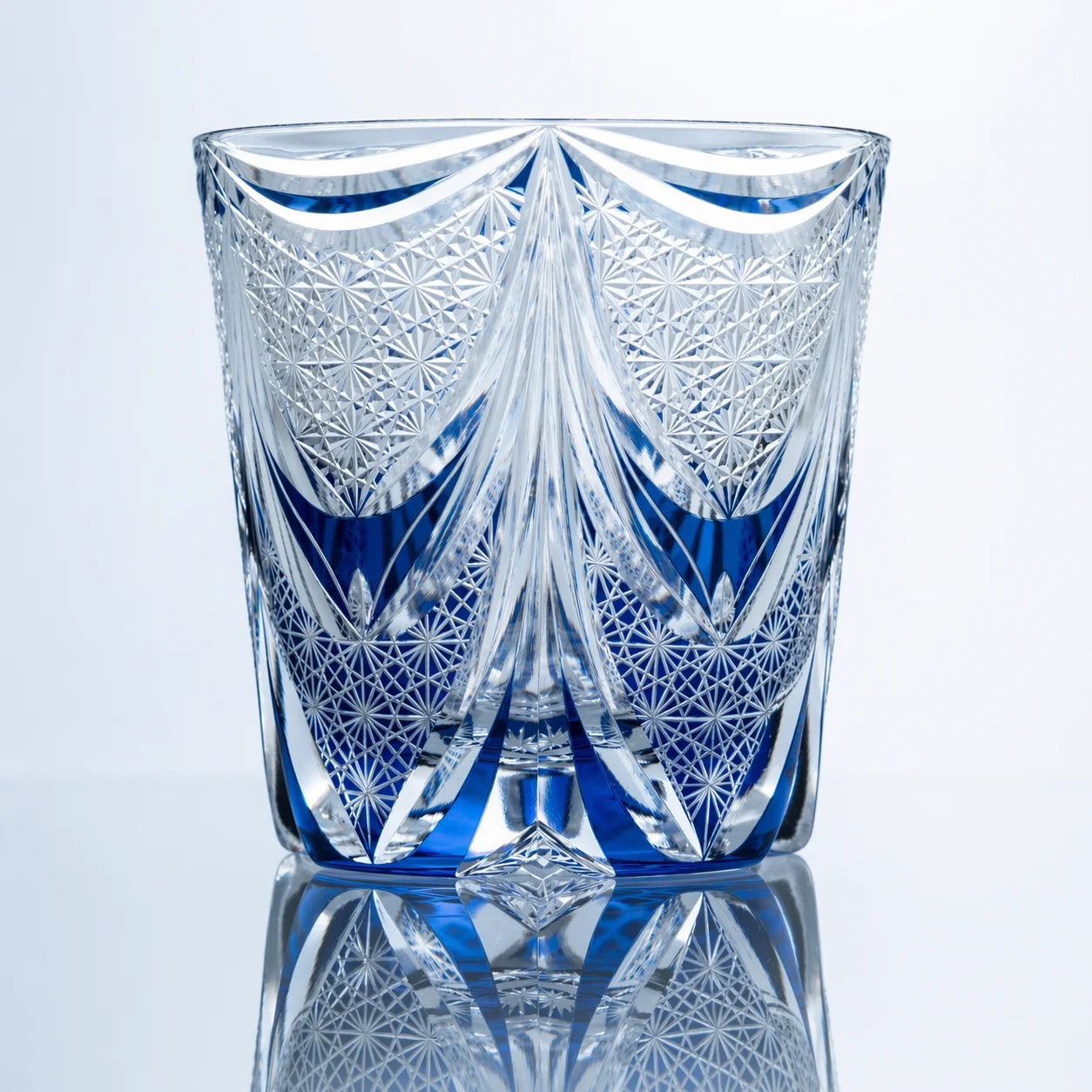 A back view of the Sapphire Veil Edo Kiriko whiskey glass showing curved crystal cuts, blue accents, geometric lattice patterns, and polished clear detailing.
