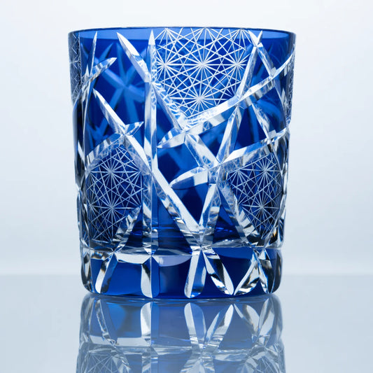 A sapphire blue hand-cut Edo Kiriko whiskey glass featuring bamboo-inspired crystal cuts, geometric starburst textures, clear faceted detailing, and a reflective studio presentation.