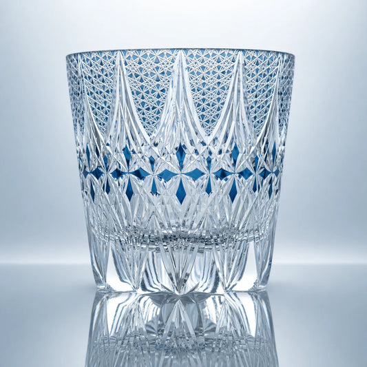 A clear hand-cut Edo Kiriko whiskey glass featuring crown-like crystal facets, blue diamond accents, intricate lattice textures, and a polished reflective studio presentation.